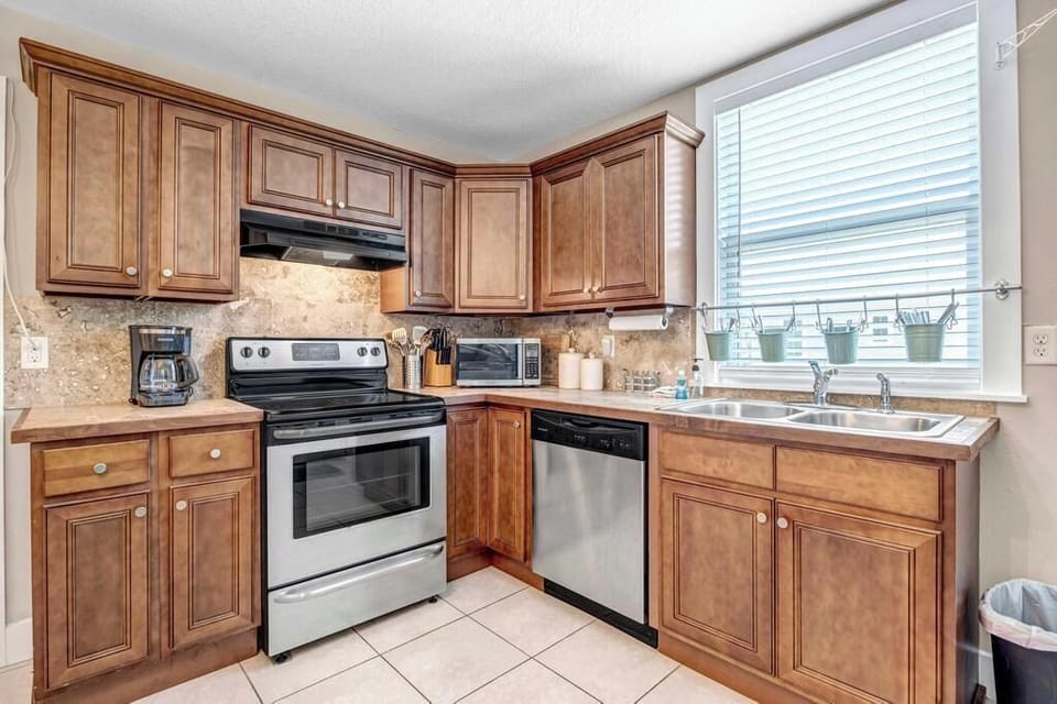 - Well equipped kitchen with stainless appliances, double sink, and plenty of counter space
- Coffee maker, microwave, toaster, and more give you all the tools to prep with ease
- Potted plants on the windowsill add warmth and character to the setup