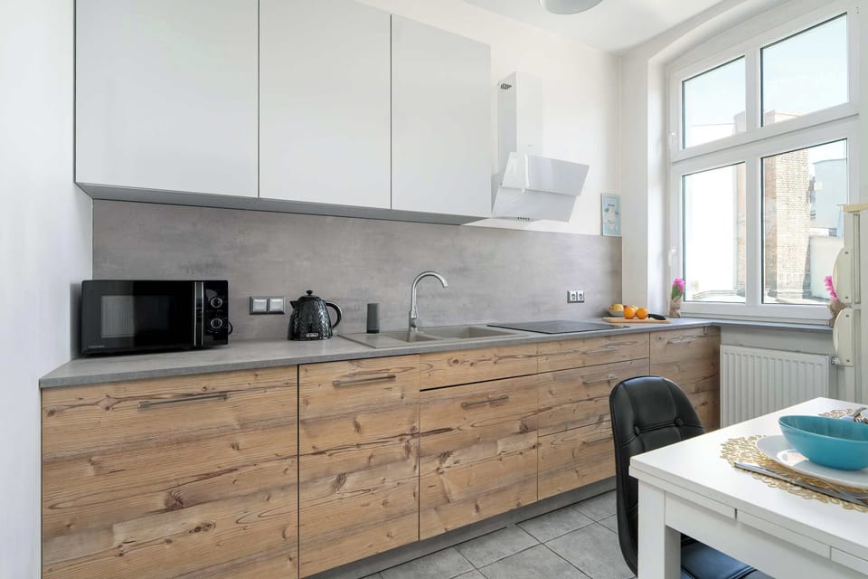 A modern kitchen with wooden fronts and white cabinets invites guests to cook together.