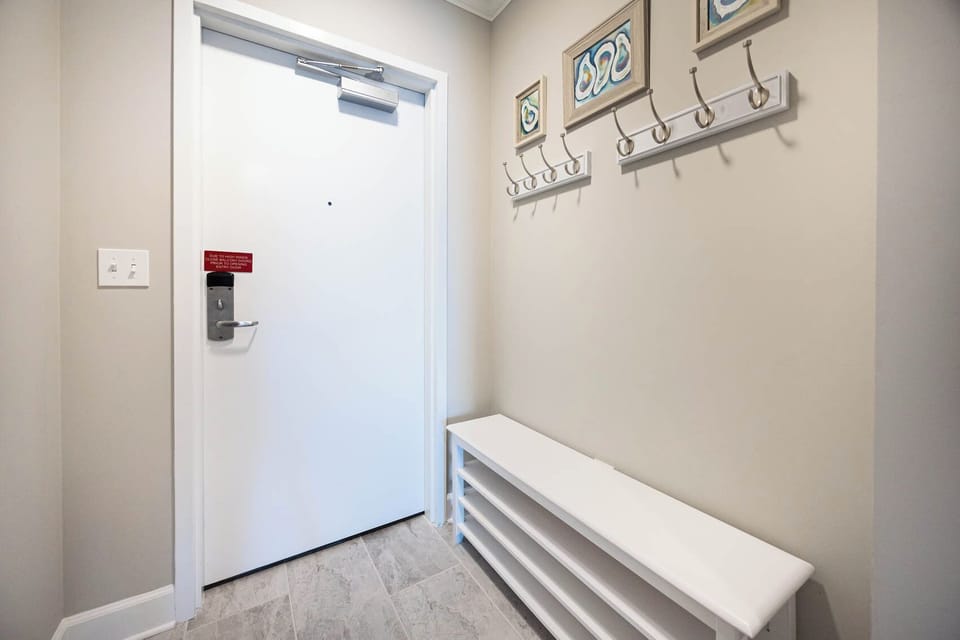 Step into a welcoming entryway featuring a sleek bench and wall hangers, inviting you to your beachfront retreat