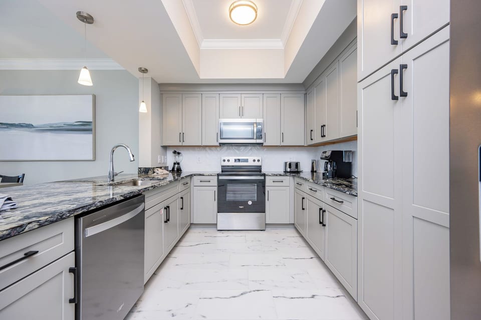 Prepare meals in this elegant kitchen featuring stunning countertops, stainless appliances, and sleek cabinetry
