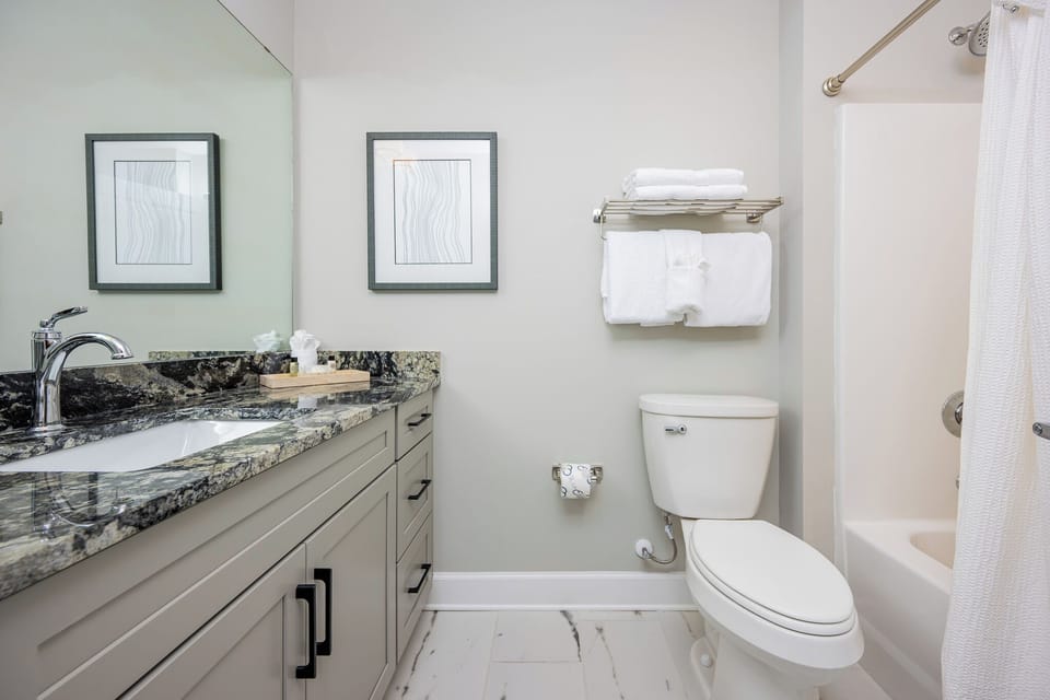 Refreshing guest bathroom with elegant granite countertops, soft towels, and tub-shower