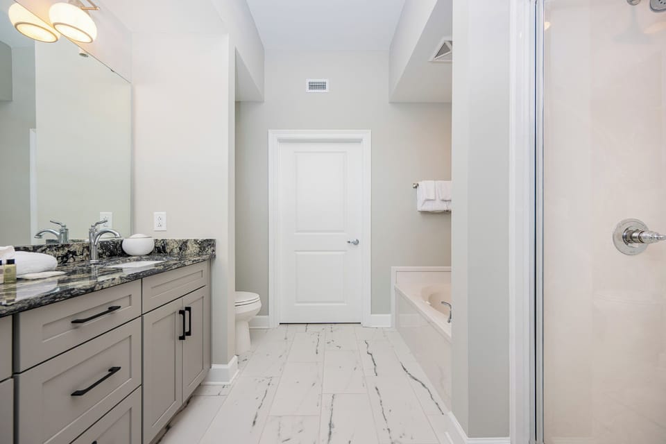 Spacious master bath featuring a stylish vanity, elegant countertops, relaxing jetted tub, and walk-in shower