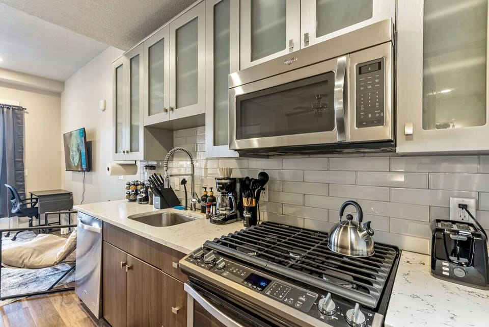 Sleek kitchen w/ gas range, marble-style backsplash & glass-front cabinets for a polished feel