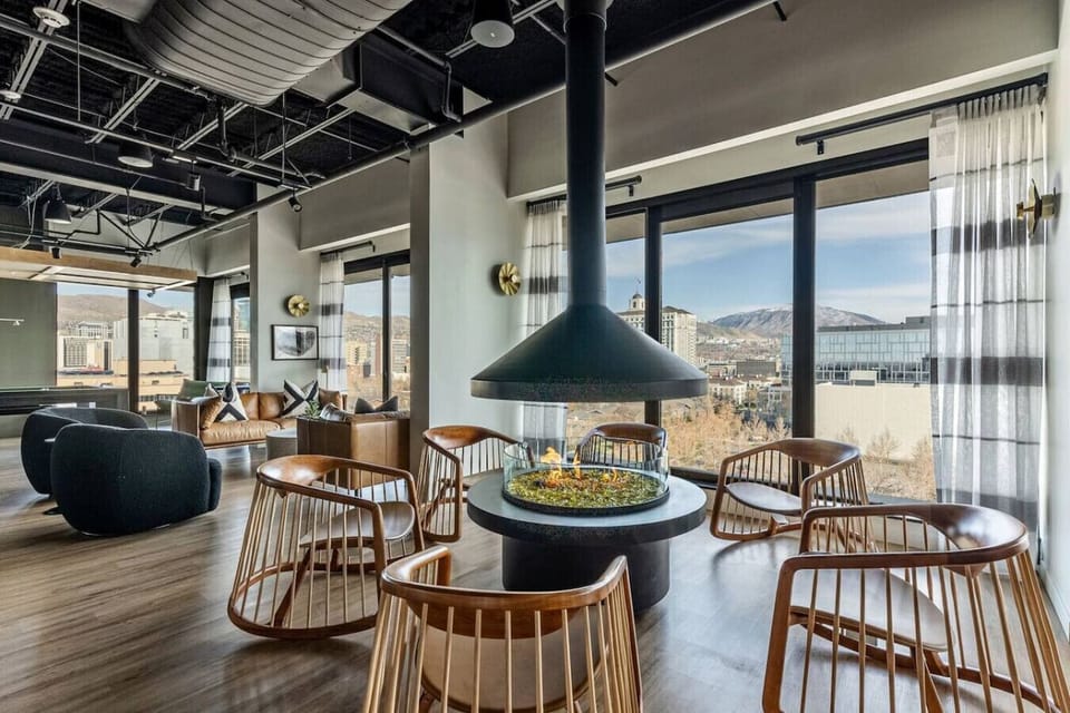 Stylish lounge w/ central fireplace, modern seating & expansive windows all around