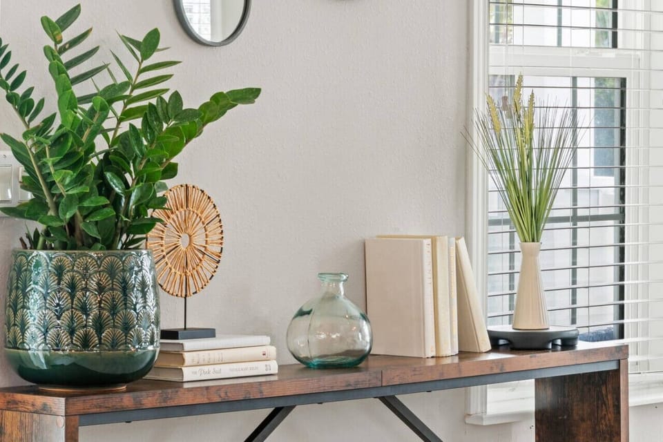 Stylish console table displays a vibrant potted plant, books, and decorative objects, adding a touch of personality to the home.
