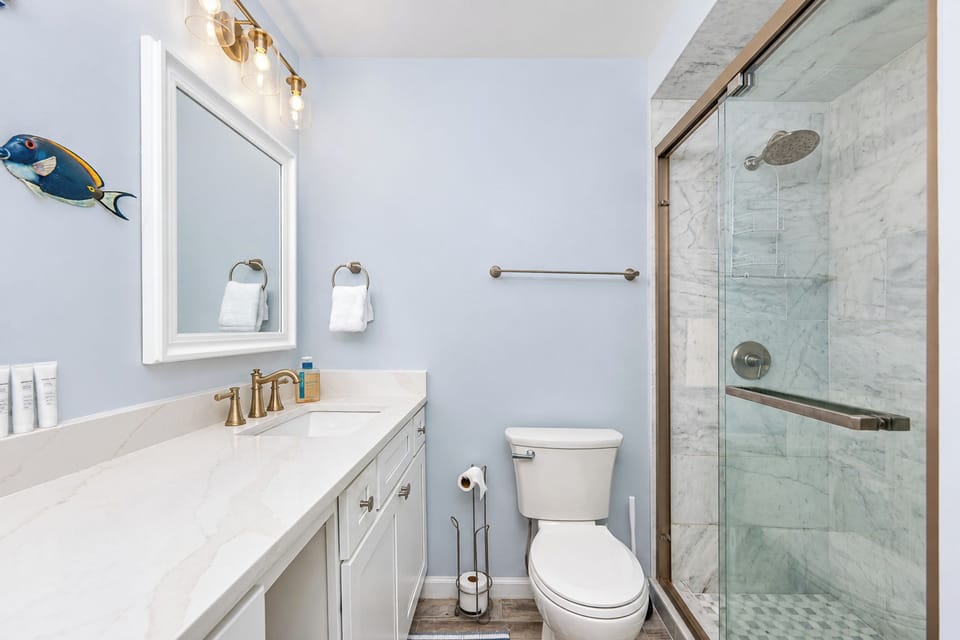 This bathroom features elegant fixtures, a spacious vanity, and a sleek glass shower for a refreshing experience