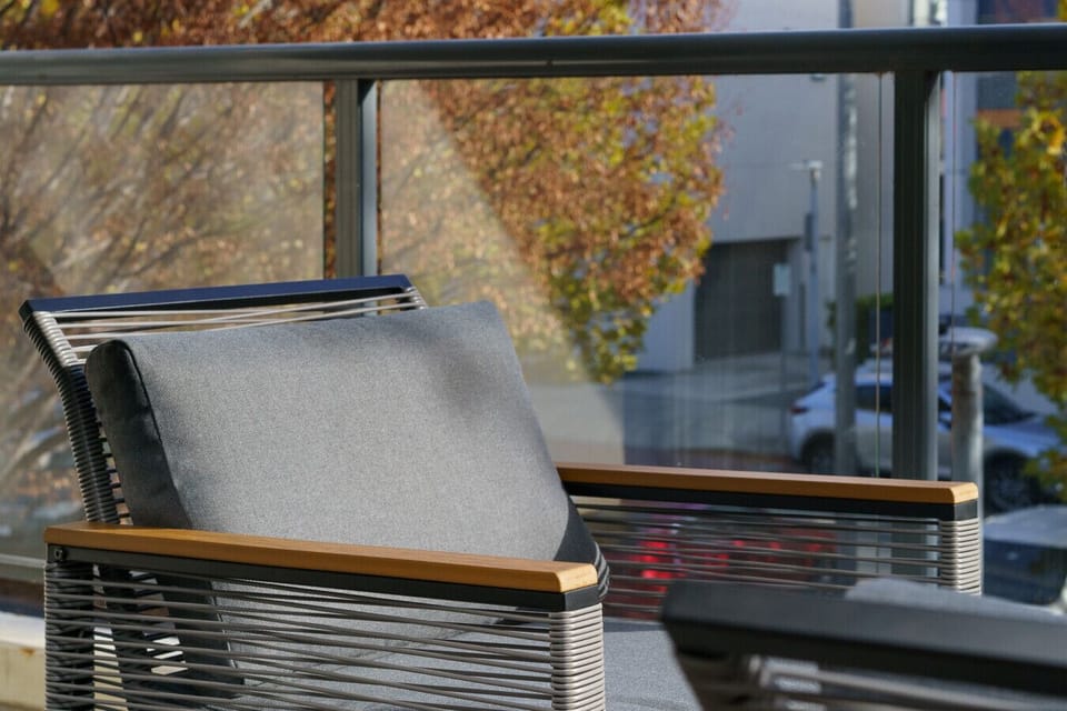 The balcony offers a comfortable outdoor seating area with a two-seater couch and two armchairs, perfect for relaxing and enjoying the fresh air.