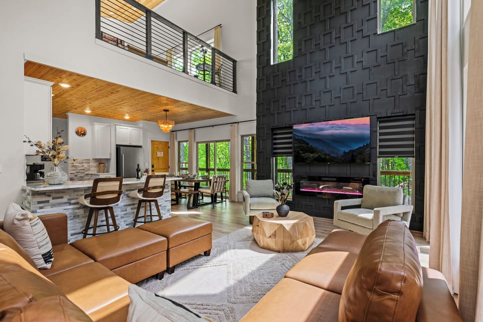 Elegant living room with high ceilings, large windows, fireplace, 75" TV & sofa.