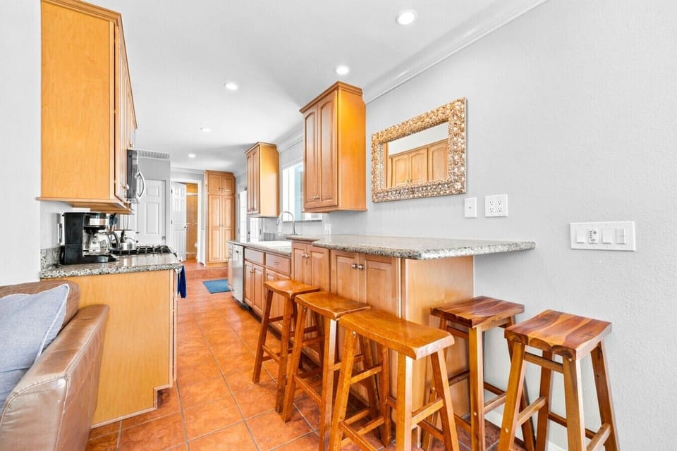 Extended granite bar seats four with handcrafted wood stools, perfect for casual meals or morning coffee, with the fully equipped kitchen just steps away.