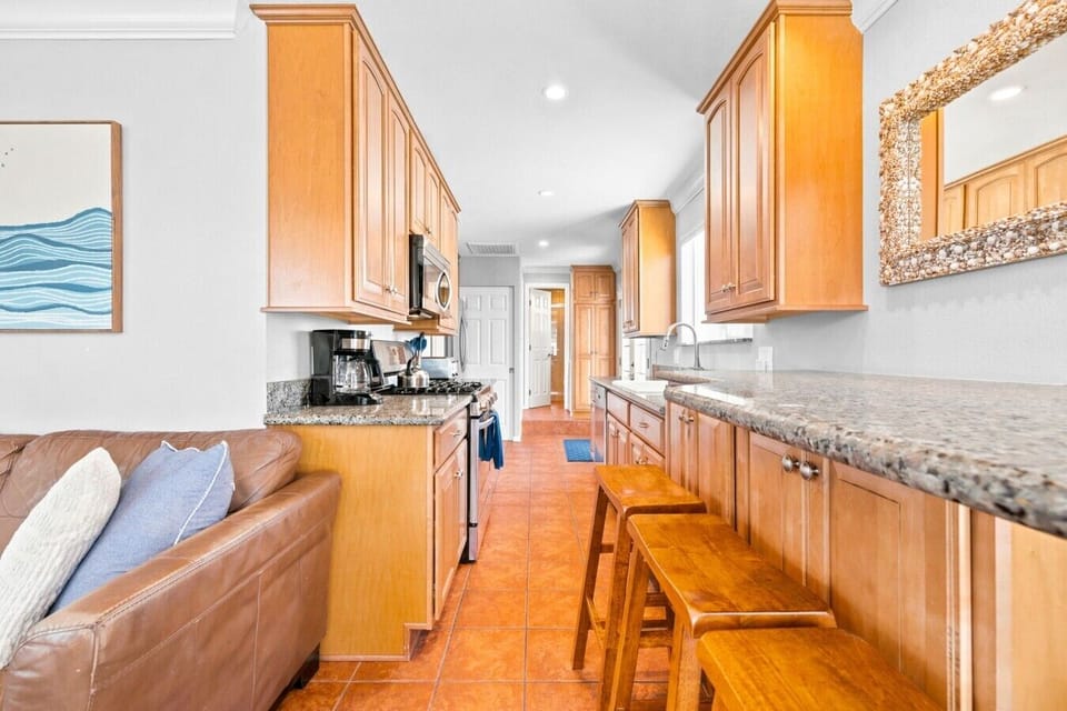 Spacious galley kitchen with bar seating for three, granite counters, and a beach-inspired mirror accent.