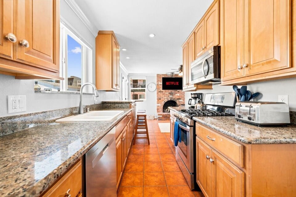 Fully equipped galley kitchen with granite countertops and stainless steel appliances, opening straight into the living area.
