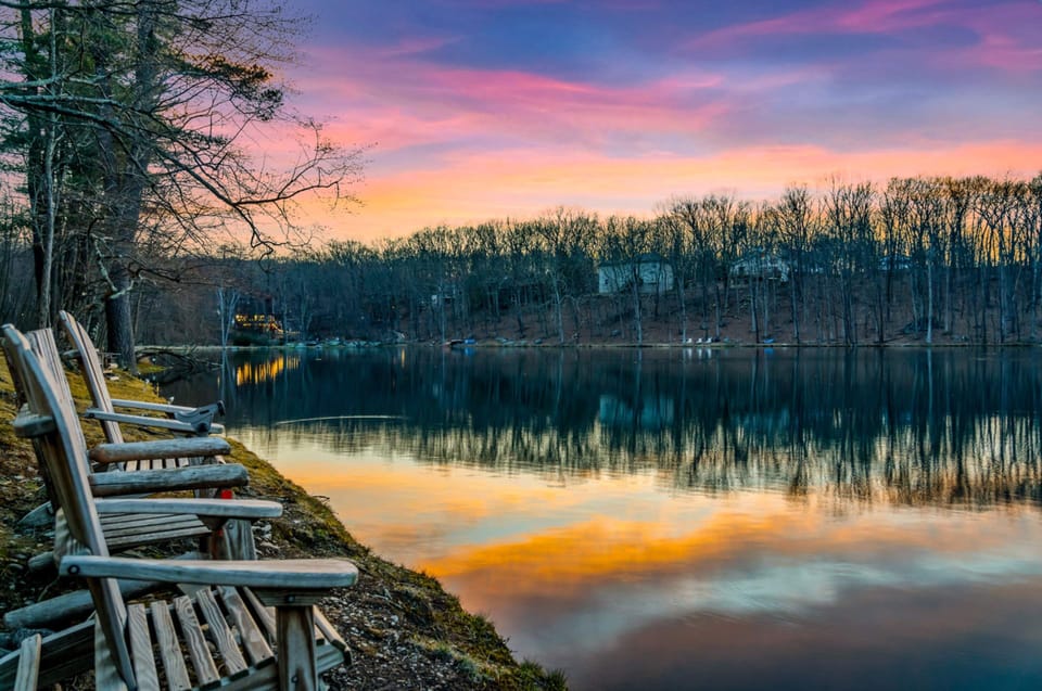 Adirondack chairs by the lake equipped with fish pole holsters