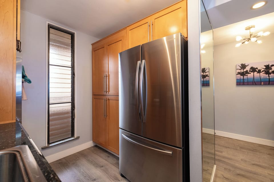 Spacious stainless steel French-door refrigerator with ample storage and adjacent pantry space—perfect for stocking up for beach picnics or sunset dinners.