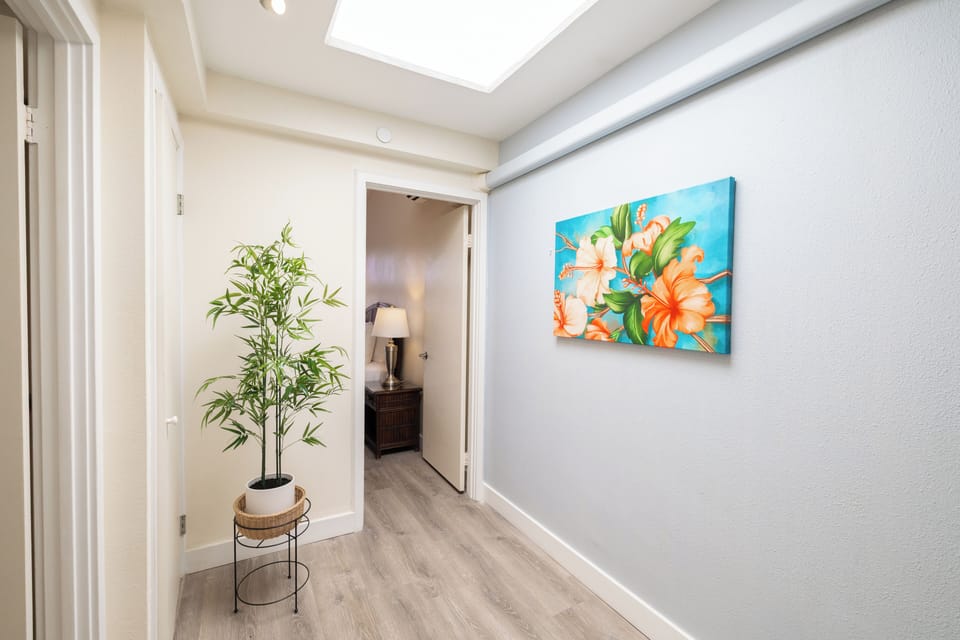 This bright hallway features a skylight, bamboo decor, and vibrant island artwork—welcoming guests into your Maui retreat with an uplifting tropical vibe.