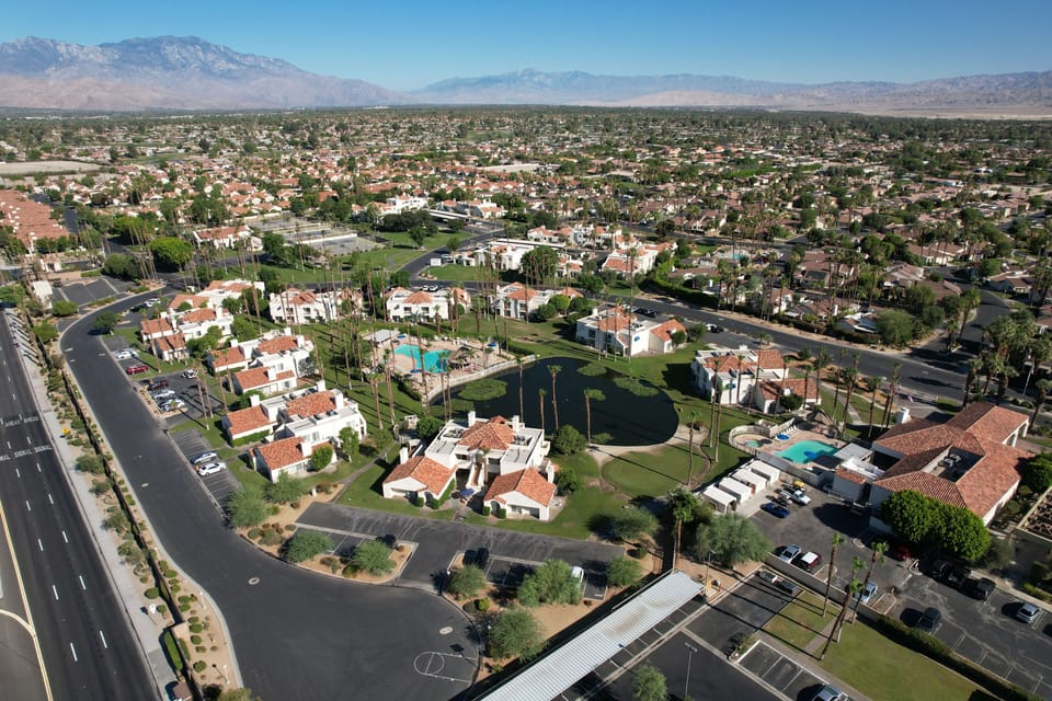 Aerial view of suburban area with residential buildings and palm trees.