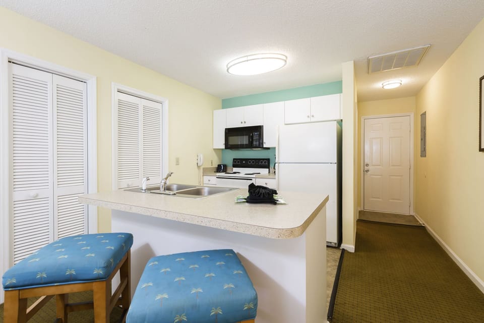 A well-equipped full kitchen awaits in this condo, complete with modern appliances and a cozy dining area, perfect for family meals.