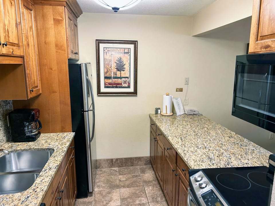 A well-appointed kitchen showcases sleek black and stainless-steel appliances, ample storage, and a cozy dining nook, ideal for family meals in a mountain resort setting.