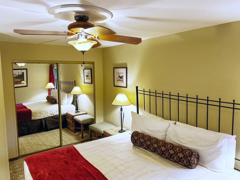 The inviting bedroom boasts a comfortable king bed, warm tones, and modern decor, complemented by an adjoining mirrored closet and cozy lighting for a restful retreat.