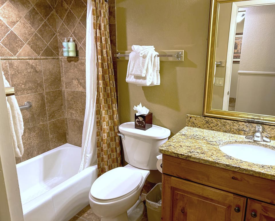 This bathroom offers a sophisticated design with granite accents, a spacious tub, and modern amenities, ensuring comfort for all guests.