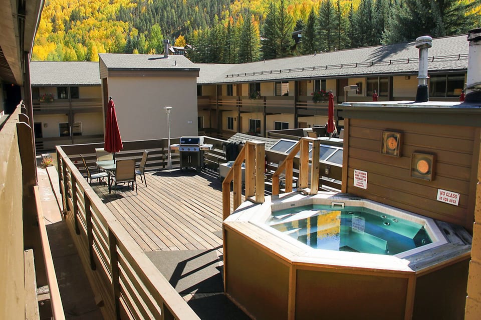Enjoy a relaxing retreat at this mountain resort featuring a shared BBQ space, shared hot tubs, and a cozy outdoor deck with picturesque views surrounded by vibrant autumn foliage.