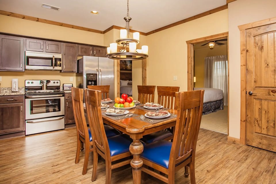 A cozy dining area features a wooden table set for a meal, surrounded by tasteful cabinetry and modern appliances, creating a welcoming atmosphere for family gatherings.