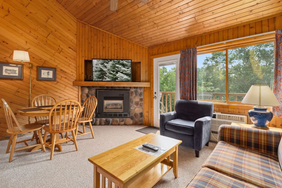 Unwind in the snug living room, complete with a stone fireplace and large windows that bring the beauty of nature indoors.