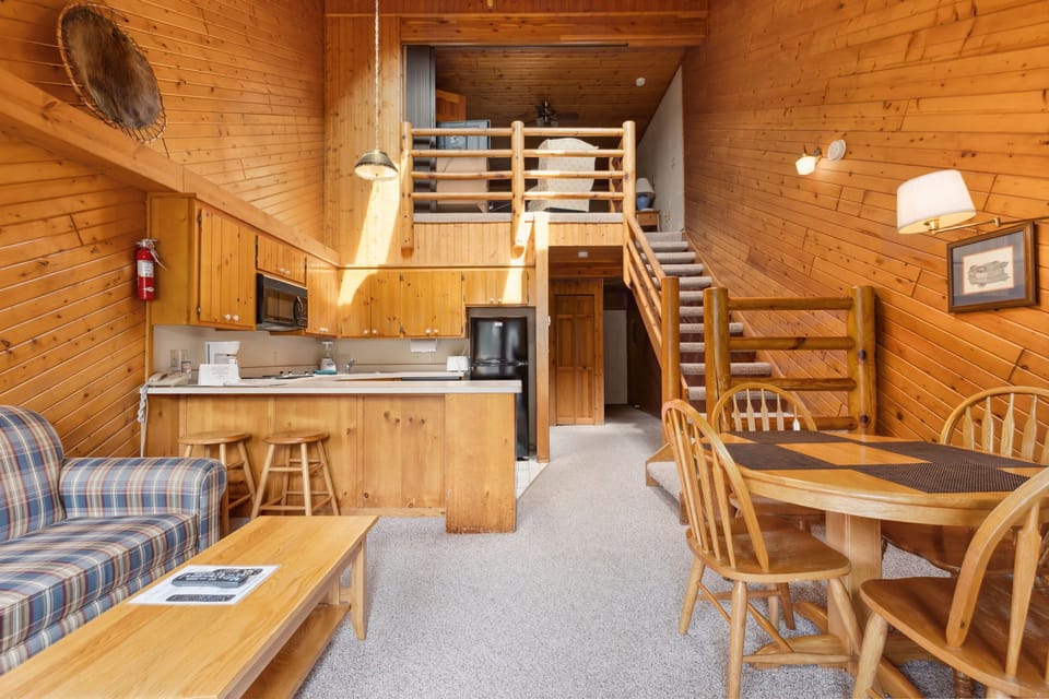 The cozy living area features rustic wood accents, a well-equipped kitchen, and a charming dining space for family meals.