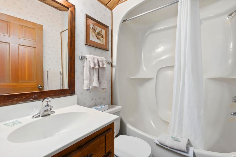 A bright and tidy bathroom showcases a clean design with modern fixtures, complemented by lovely artwork for a touch of warmth.