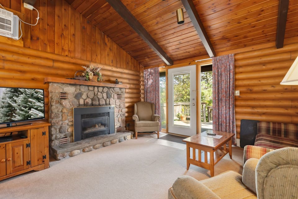 Spacious living room with a stone fireplace and natural wood interiors, perfect for gathering.
