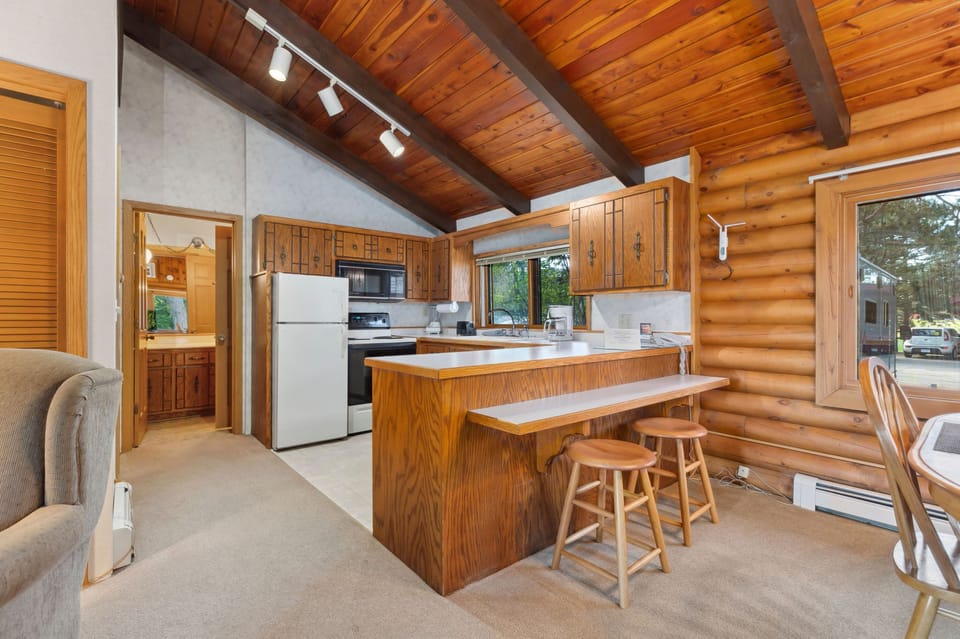 Open kitchen with rustic wood cabinetry, modern appliances, and a breakfast bar.