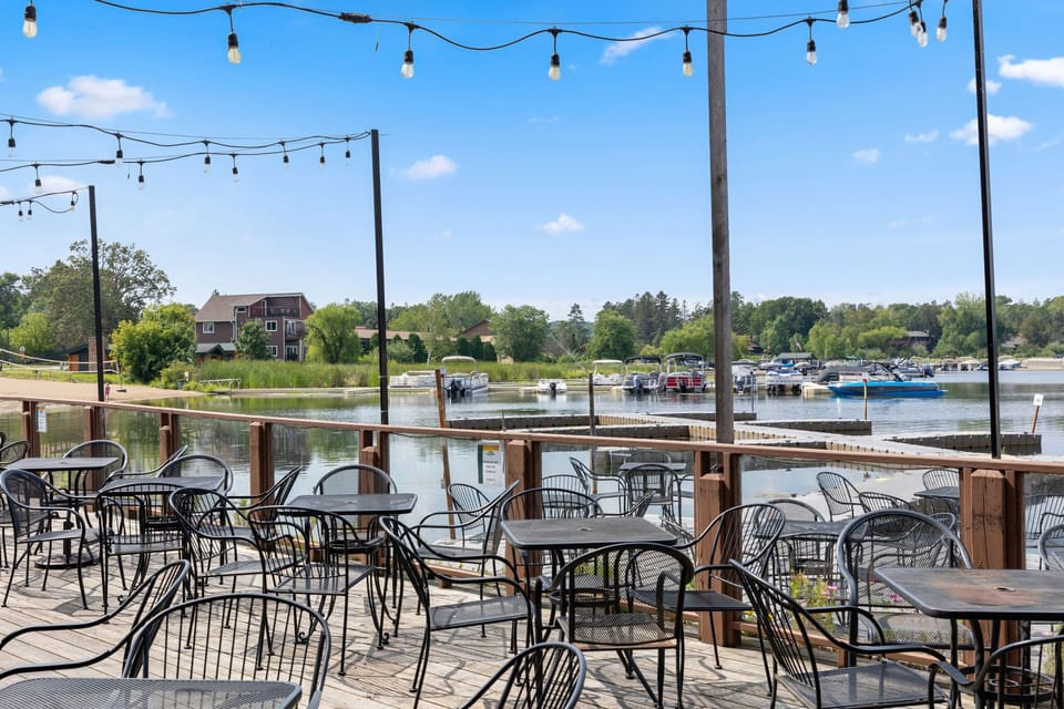 Lakeside patio with string lights and seating, perfect for outdoor dining by the water.