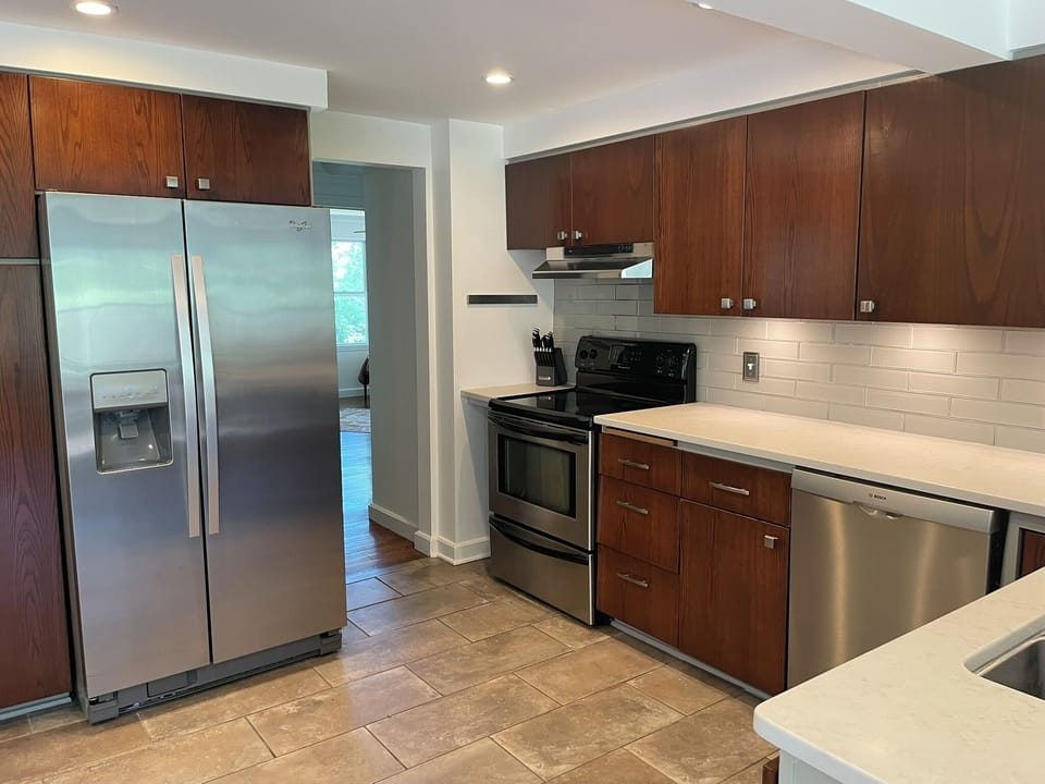 Fully equipped kitchen with plates, glasses, cookware, bakeware, and utensils.
