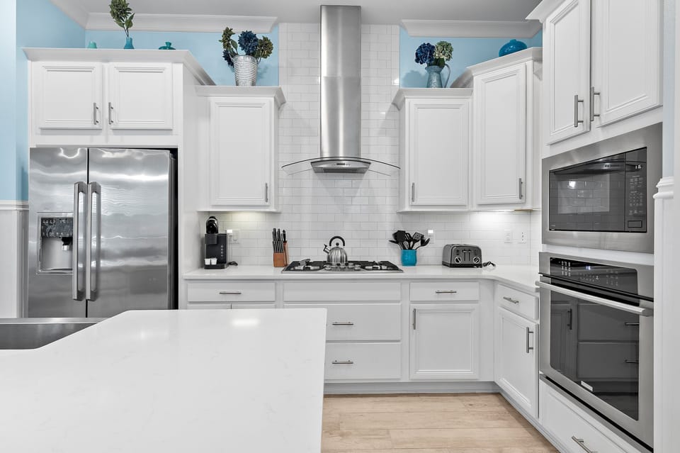 A crisp white chef's kitchen with stainless appliances and everything you need to cook in.