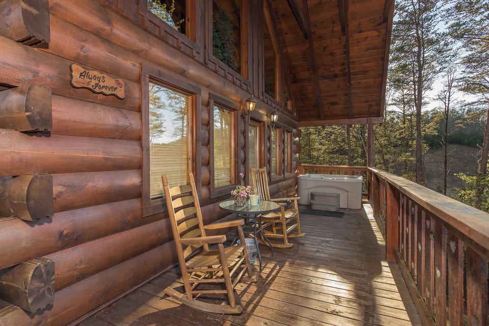 rocking chairs and hot tub on a covered deck at always & forever a 1 bedroom cabin rental located in pigeon forge