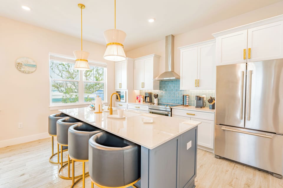 Beautifully renovated kitchen featuring gold finishes, a bold blue backsplash, and coastal boho vibes throughout.
