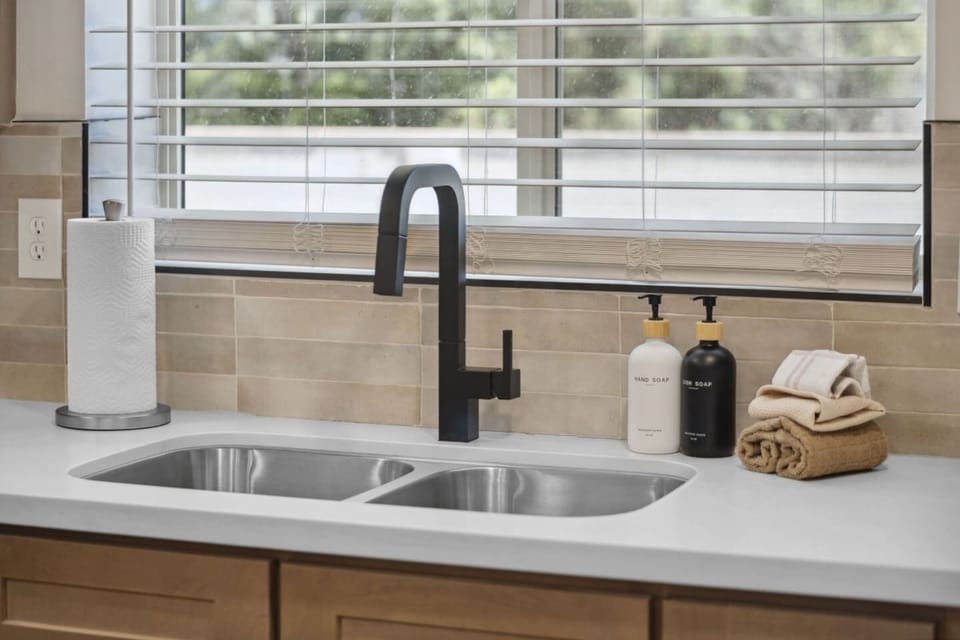 Kitchen sink w/ window light, modern faucet & practical prep space.