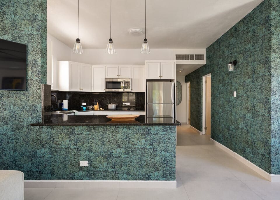 Modern kitchen with sleek white cabinetry, black countertops, stylish pendant lighting, and plenty of natural light—perfect for cooking and gathering!