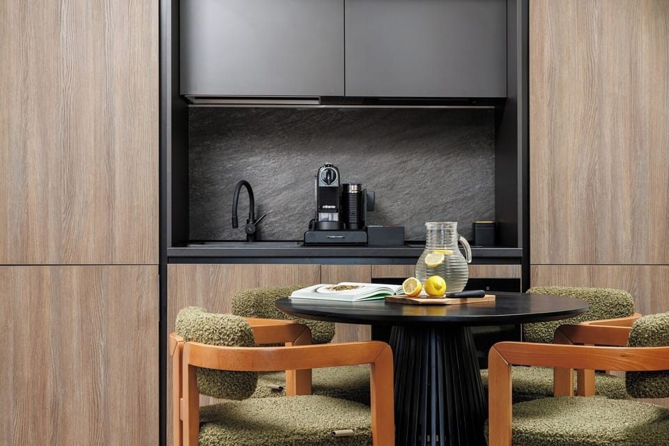 Modern black-and-wood kitchenette equipped with a stylish sink, espresso machine, and dark textured backsplash. Perfect for preparing coffee or a quick breakfast before mountain adventures.