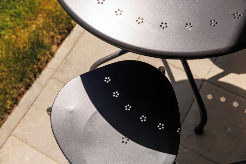 Chic outdoor seating with floral-cutout metal chairs and coffee table, perfect for enjoying your morning espresso surrounded by fresh mountain air.