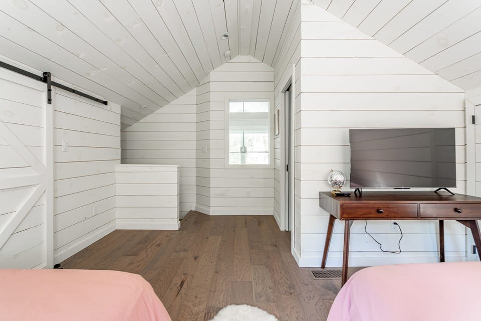 Roomy sleeping area with twin full beds, bright windows, and workspace.