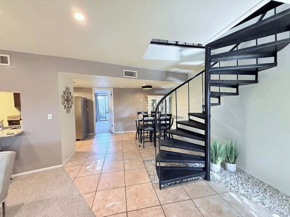 At the heart of the space, a stunning spiral staircase serves as a sculptural focal point, leading gracefully up to a expansive loft area. 