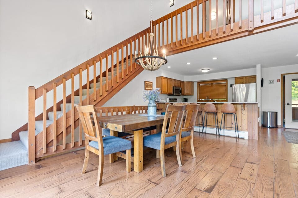 Enjoy meals and connection in this open-concept dining area with rustic charm, antler chandelier, and seating for six—right next to the kitchen and bar stools.
