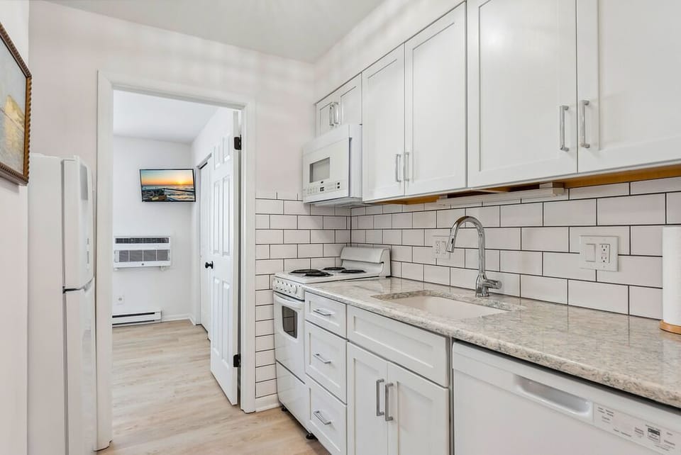 Bright kitchen featuring white cabinetry and essential appliances.
