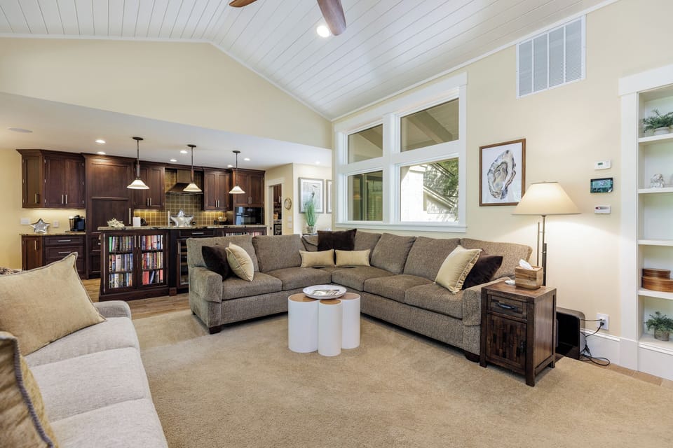 This welcoming living area features vaulted ceilings with crisp beadboard detail, recessed lighting, and a ceiling fan that keeps the space comfortable year-round.