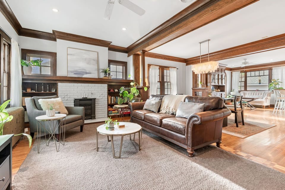 Relax in your elegant living room with rich wood trim, a cozy leather sofa, and charming fireplace creating the perfect atmosphere for unwinding.