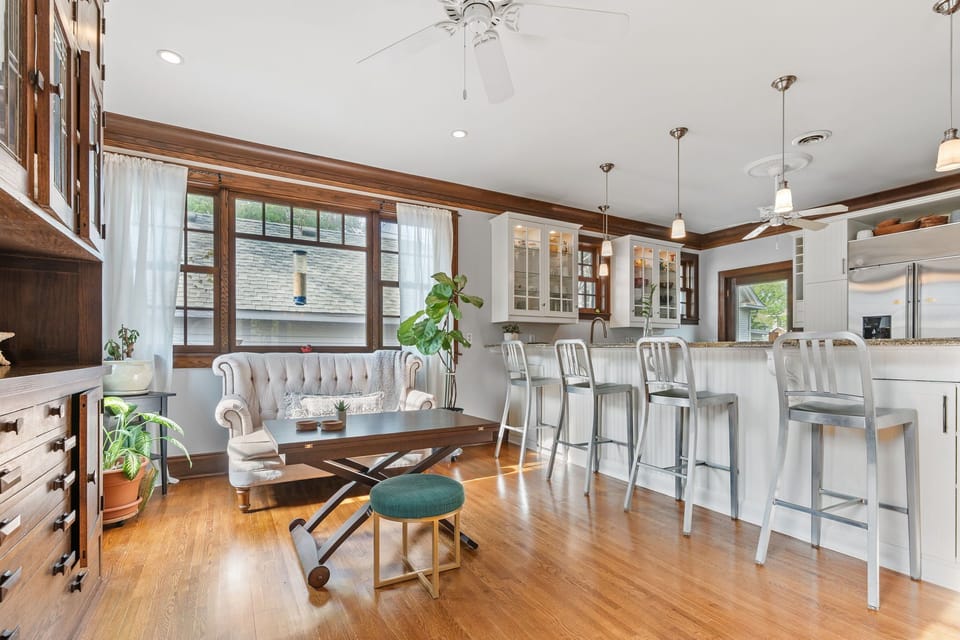 Your open-plan living space blends comfort and functionality with rich wood floors, elegant pendant lighting, and a kitchen island perfect for morning coffee.