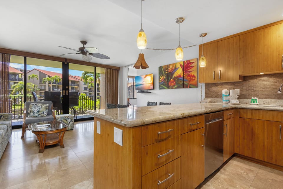 Relax in this open-concept living space with warm wood tones, granite countertops, and tropical flair—your island kitchen awaits with serene balcony views beyond.