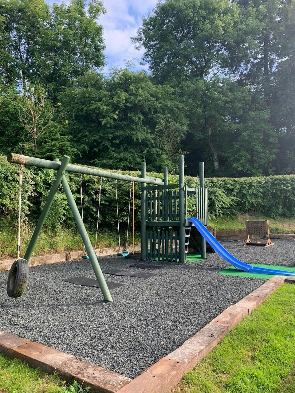 Outdoor play area with swings, climbing frame and slide