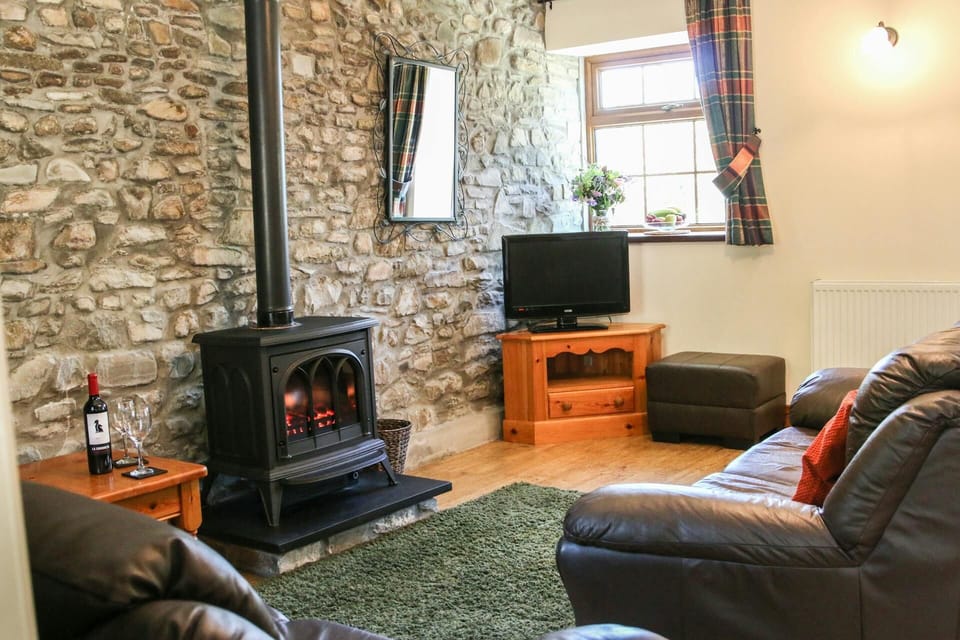 Lounge with woodburner, sofa, footstool, TV on unit and wall mirror