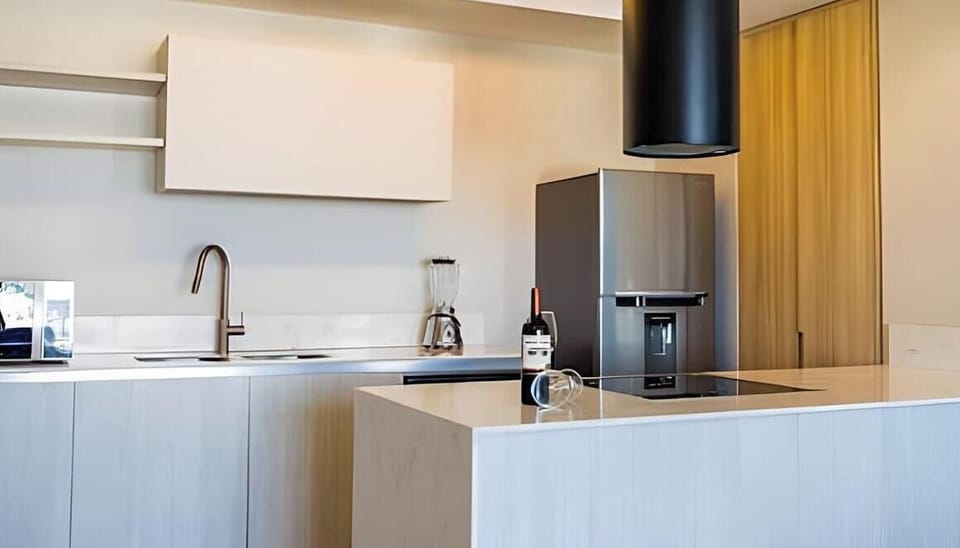 Modern kitchen w/ clean lines, warm wood accents & sleek counters